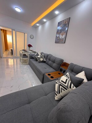 A modern living room with a grey sofa set, a wooden coffee table, and a painting on the wall. - Private Apartment in Hurghada (Égypte hurgada)