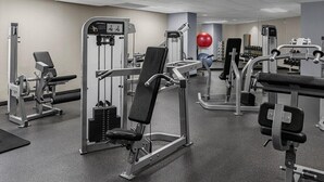Ein Fitnessstudio mit verschiedenen Trainingsgeräten, darunter Krafttrainingsmaschinen und Kurzhanteln.