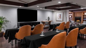 Ein Konferenzraum mit Tischen, Stühlen, einem großen Bildschirm und einem Kamin.