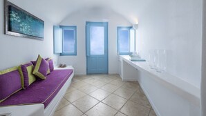 A room with a purple sofa, a blue door, and a window. - Lioren Suite, Divine Sea Views, Santorini (Santorini)