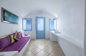 A room with a purple sofa, a blue door, and a window. - Lioren Suite, Divine Sea Views, Santorini (Santorini)