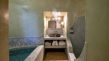 Ein Badezimmer mit gefliestem Boden, einem Waschbecken mit Spiegel und einer Badewanne.