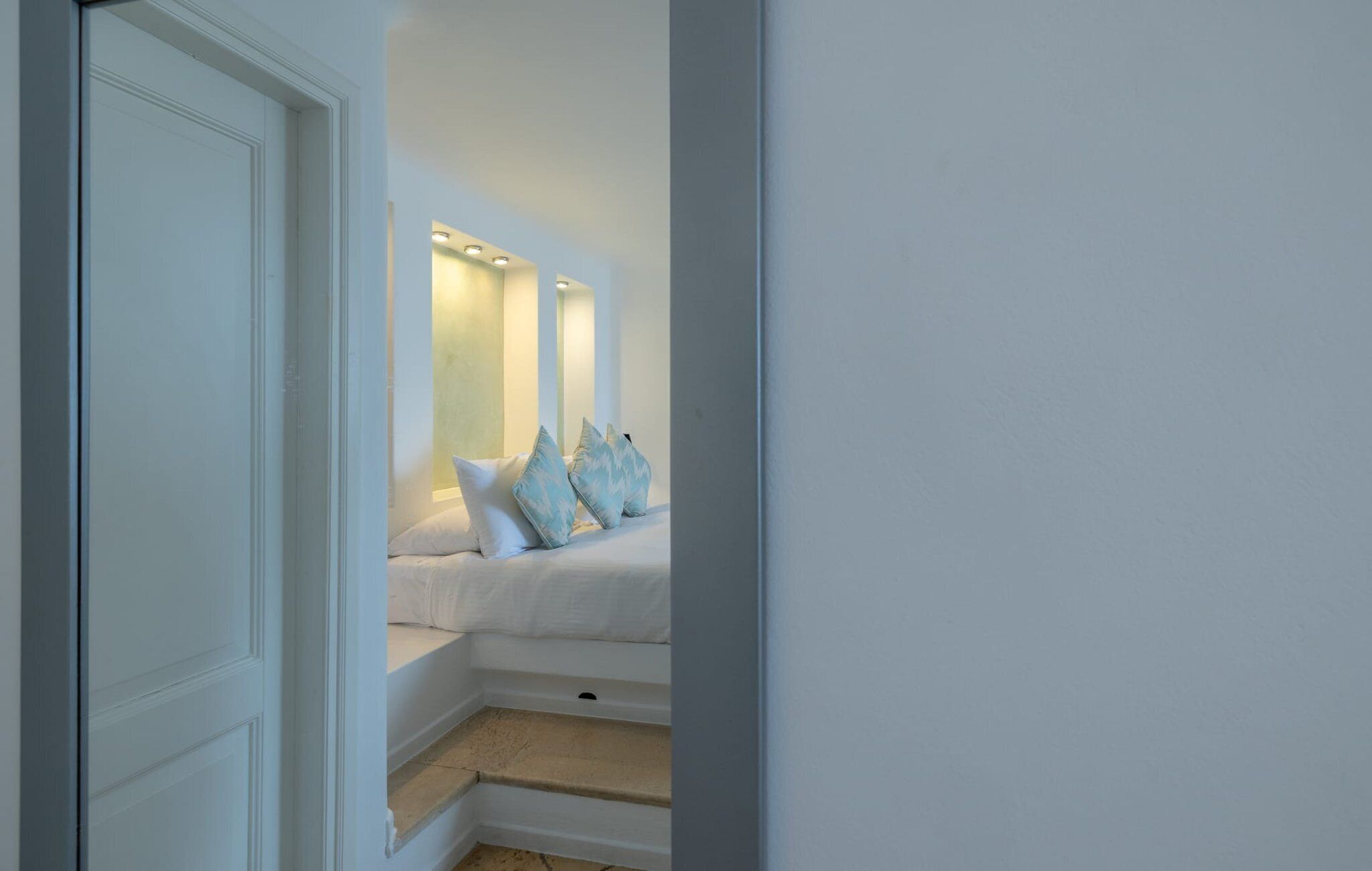 A bedroom with a bed, pillows, and a nightstand.