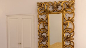 Ein Zimmer mit einem Bett, einem weißen Kleiderschrank und einem großen, verzierten Spiegel.