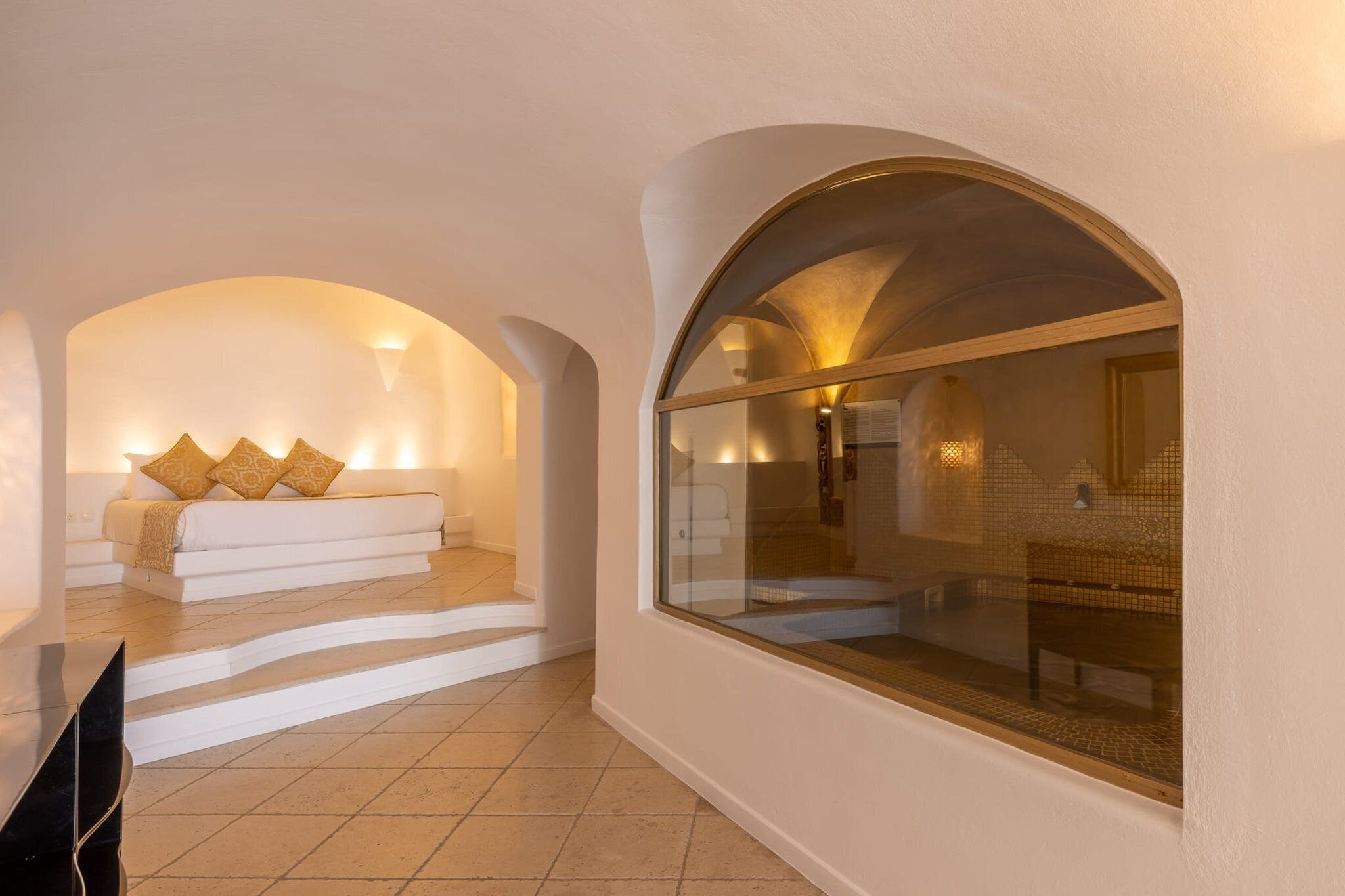 A modern interior with a white sofa set, a glass window, and a tiled floor.