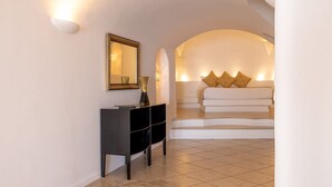 Ein modernes Hotelzimmer mit einer schwarzen Konsole, einem Spiegel und einem Bett mit weißer Bettwäsche und dekorativen Kissen.