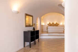 A modern hotel room with a black console table, a mirror, and a bed with white bedding and decorative pillows. - Elysora Suite, Divine Sea Views, Outdoor & Indoor Jacuzzi, Santorini (Santorini)