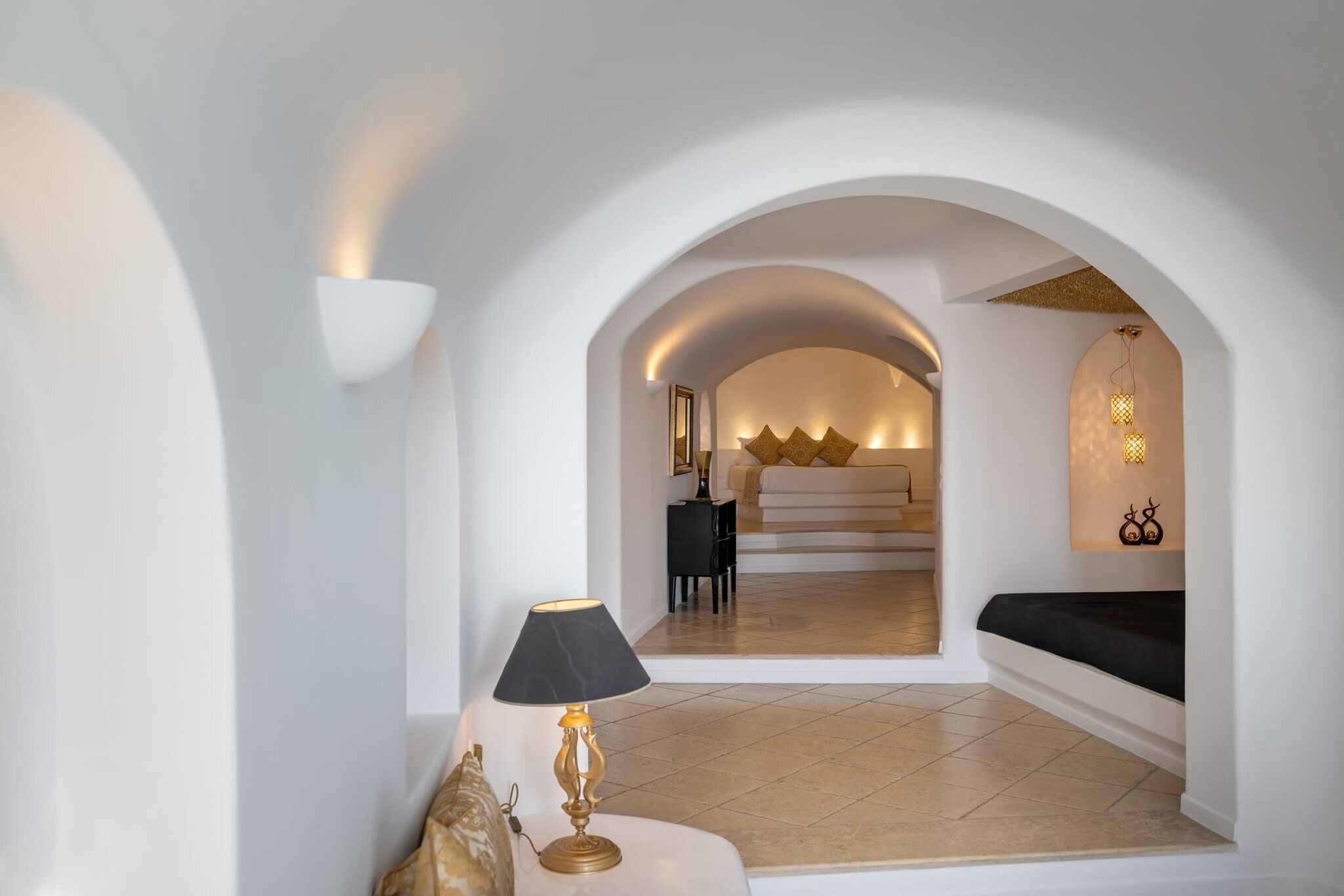 Ein modernes Interieur mit einem Rundbogen, der in ein Schlafzimmer führt, einer Couch und einer Lampe.