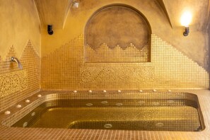 A spa room with a bathtub, tiled walls, and a decorative arch. - Elysora Suite, Divine Sea Views, Outdoor & Indoor Jacuzzi, Santorini (Santorini)