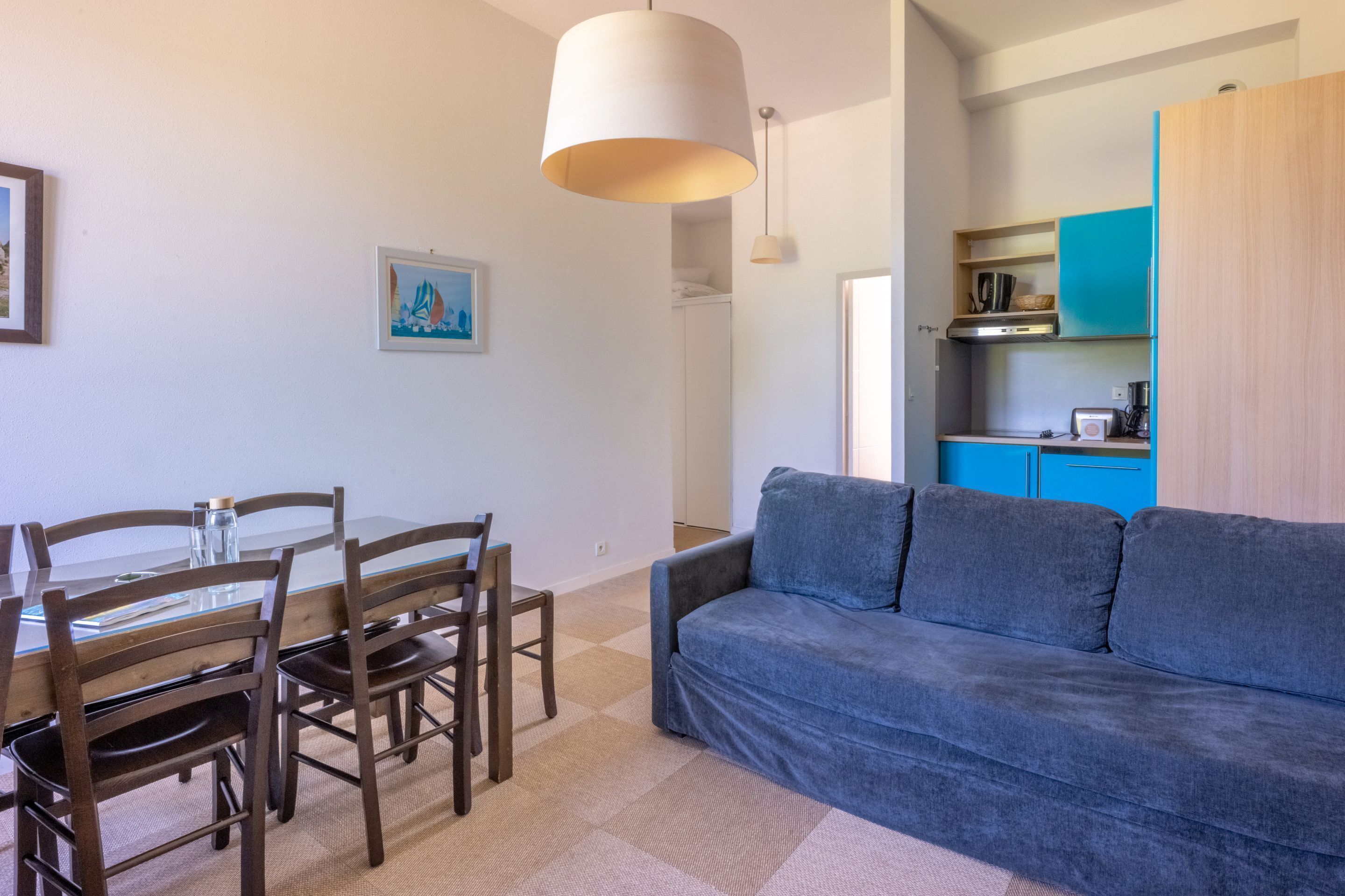 Een moderne woonkamer met een blauwe bank, een houten eettafel en stoelen.