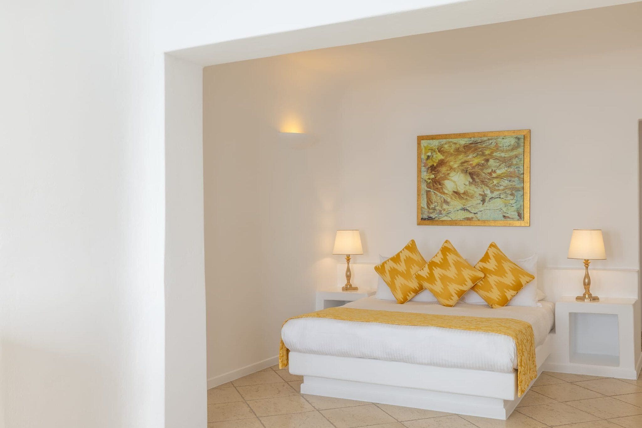 Een slaapkamer met een bed, twee nachtkastjes, lampen en een schilderij aan de muur.