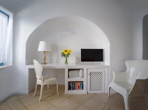 A white study area with a desk, two white chairs, a lamp, a vase with flowers, a TV, and a bookshelf. - Coralyon Suite, Divine Sea Views, Outdoor Jacuzzi, Santorini (Santorini)