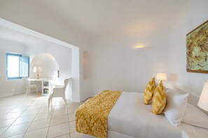 Ein Hotelzimmer mit Bett, Nachttischlampen, Schreibtisch mit Stuhl und einem Fenster mit Vorhängen.