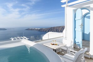 A seaside terrace with a pool, white furniture, and a view of the ocean and cliffs. - Coralyon Suite, Divine Sea Views, Outdoor Jacuzzi, Santorini (Santorini)