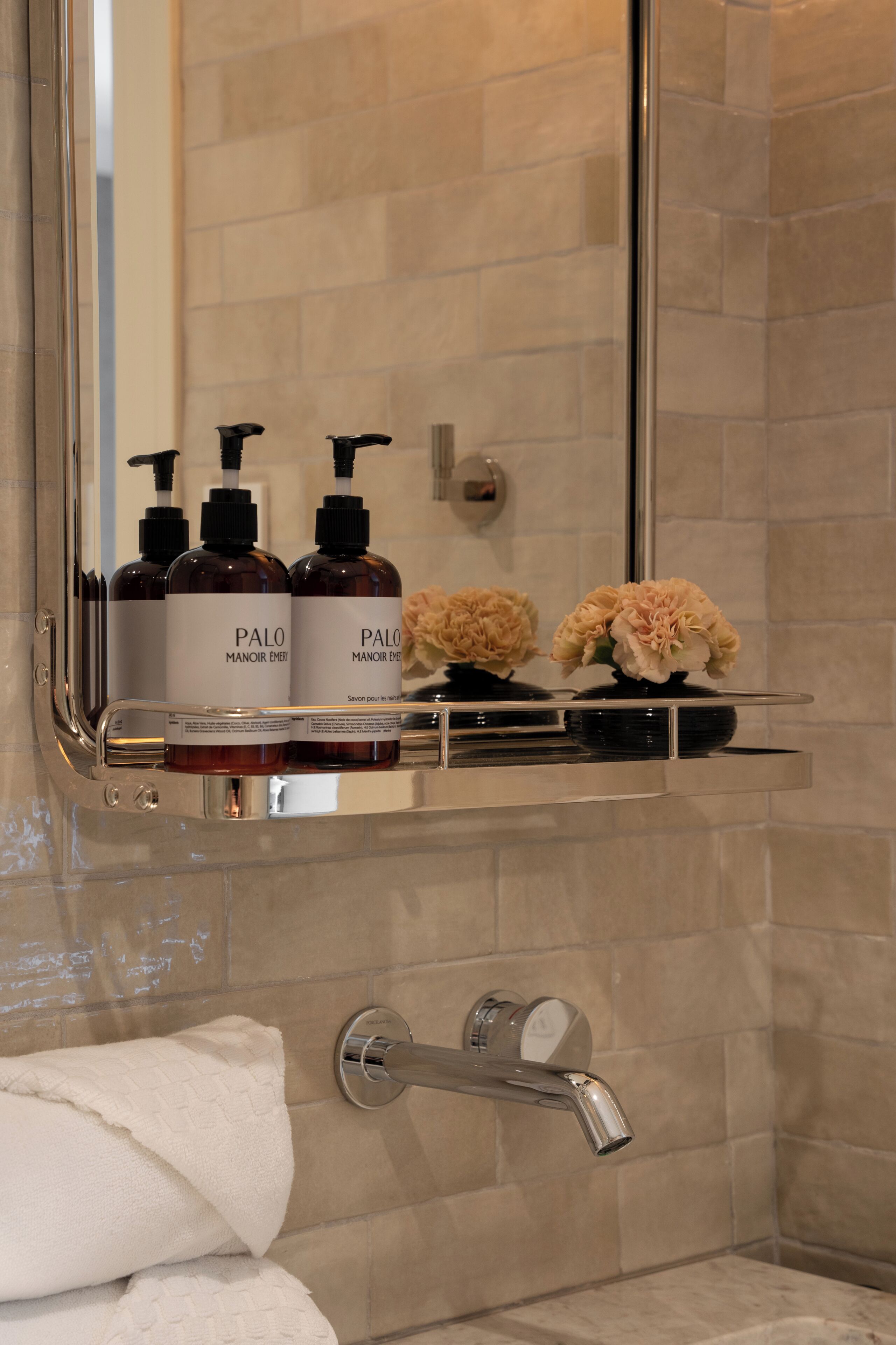 A bathroom with a mirror, toiletries, a towel, and a shower.