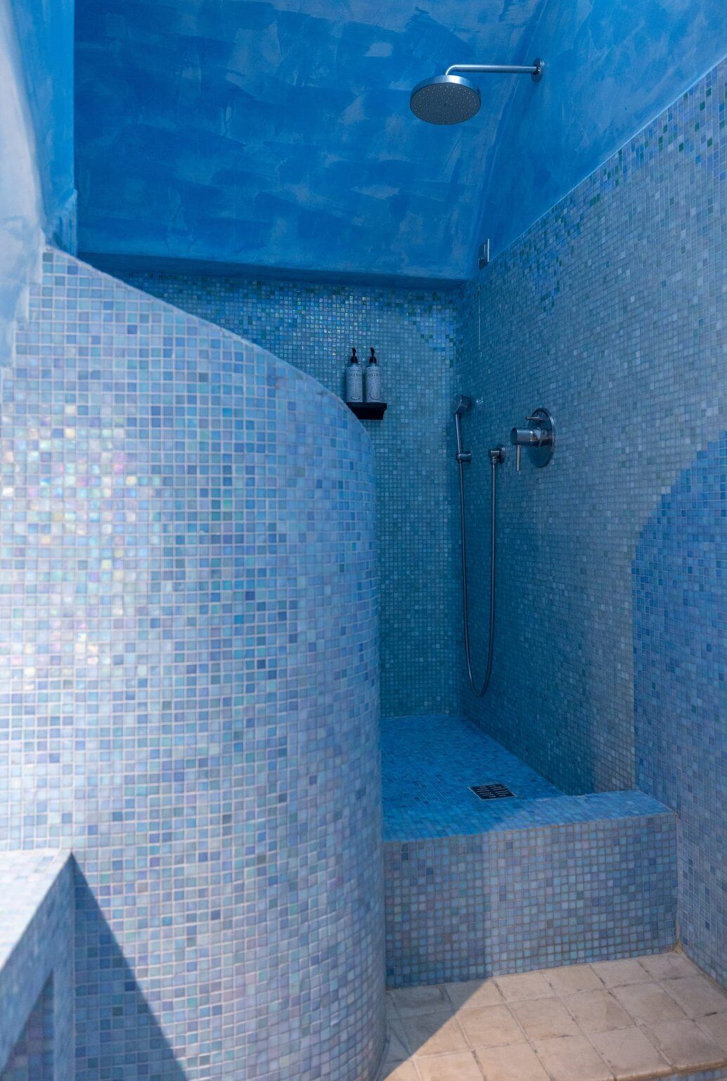 Une petite salle de douche carrelée, équipée d’un pommeau de douche et d’un flexible de douche.