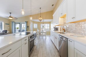 A kitchen with white cabinets, stainless steel appliances, and pendant lighting.