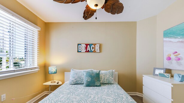 Une chambre à coucher comprenant un lit, une table de chevet, une lampe, un panneau fixé au mur et un tableau.