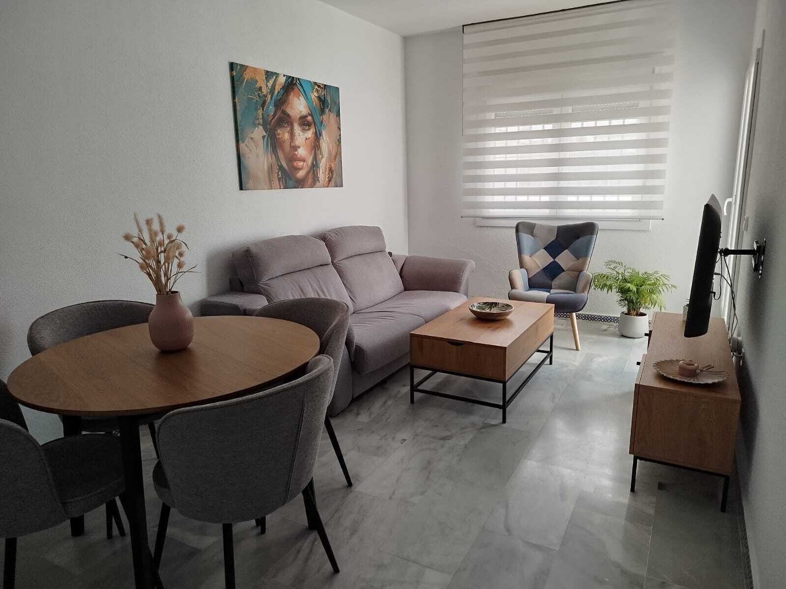 A modern living room with a sofa, a coffee table, a dining table with chairs, a TV, and a window with blinds.