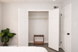 A bedroom with a bed, a potted plant, a bench, and a closet with open doors. - 2BR Atlanta Home Base: Airport Access + Workspace (Jonesboro)