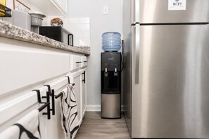 A kitchen with a stainless steel refrigerator, a water dispenser, and white cabinets. - 2BR Atlanta Home Base: Airport Access + Workspace (Jonesboro)
