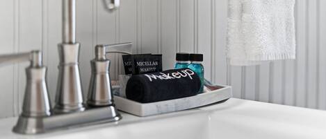 Un lavamanos con grifo, una toalla y productos de maquillaje.