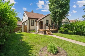 A two-story house with a front porch, a visible number '5', and a well-maintained lawn. - Magnolia House (Minneapolis)
