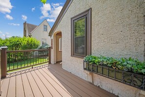 A wooden deck with a railing, a white textured wall, and a window. - Magnolia House (Minneapolis)