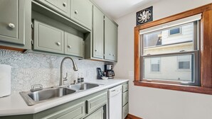 Eine Küche mit zwei Spülen, einem Geschirrspüler und einem Fenster mit Blick auf eine Wohngegend.