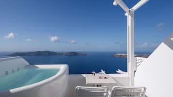 Ein Balkon mit Meerblick, eine weiße Badewanne sowie ein Tisch mit einem Weinglas und einer Speiseplatte.