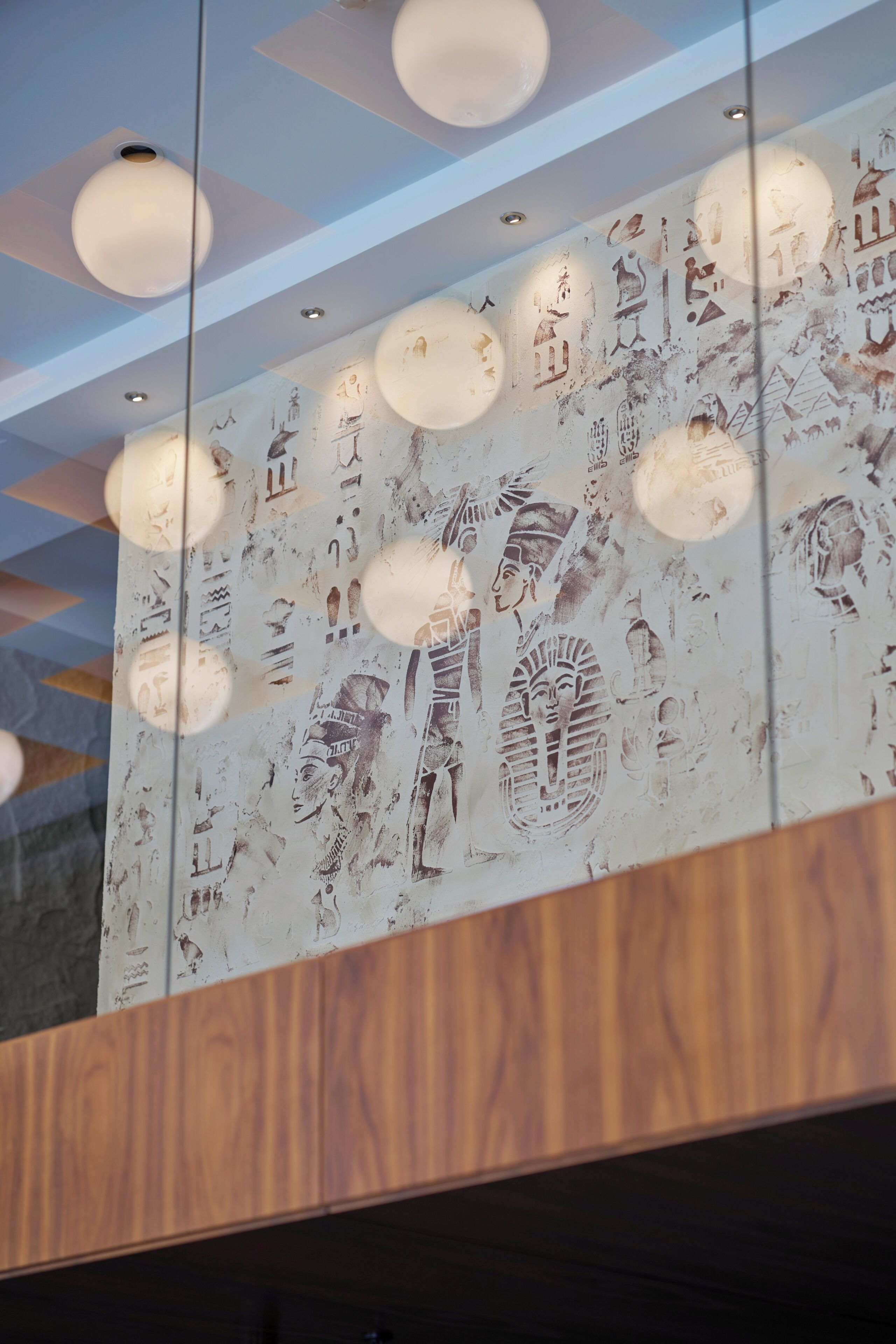 A ceiling with recessed lighting and wall art depicting ancient Egyptian hieroglyphs.
