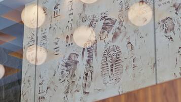 A ceiling with recessed lighting and wall art depicting ancient Egyptian hieroglyphs.