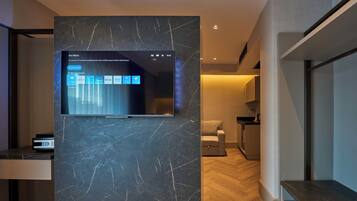 A modern living room with a flat-screen TV mounted on a marble wall, a sofa, and a coffee table.