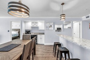 A modern kitchen with white cabinetry, a marble countertop, and pendant lighting. - Seagate 407 (Indian Shores)