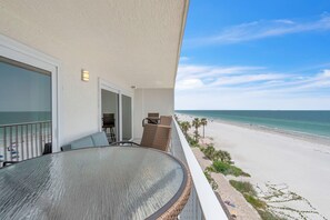 A balcony with a glass table and chairs, overlooking a beach with palm trees and a clear sky. - Seagate 407 (Indian Shores)