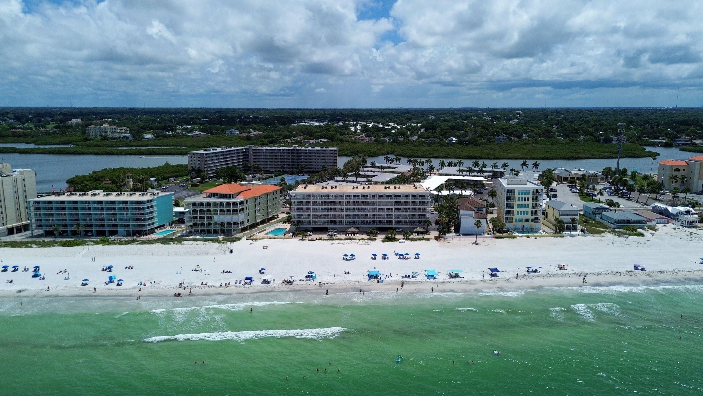 A coastal hotel with multiple buildings, a beachfront, and a view of the ocean.