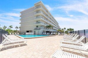 A hotel with a pool, multiple balconies, and sun loungers. - Seagate 407 (Indian Shores)