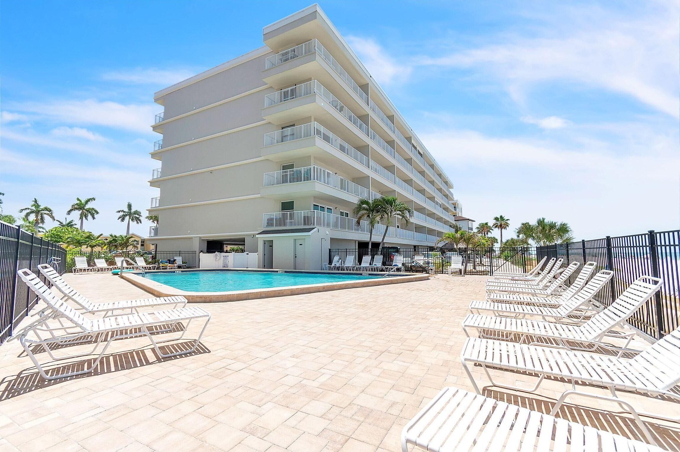 Un hotel con piscina, varios balcones y sillones de sol.
