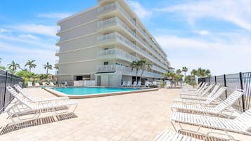 Un hôtel doté d’une piscine, de plusieurs balcons et de chaises longues.