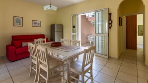 A dining area with a table, chairs, a red sofa, and a refrigerator. - Villa Micelli by BarbarHouse (Campomarino)