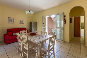 A dining area with a table, chairs, a red sofa, and a refrigerator. - Villa Micelli by BarbarHouse (Campomarino)