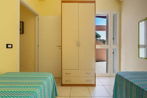 A room with two beds, a wardrobe, and a door leading to an outdoor balcony. - Villa Micelli by BarbarHouse (Campomarino)