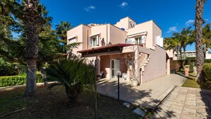 A modern two-story building with a flat roof, surrounded by palm trees and a paved walkway. - Villa Micelli by BarbarHouse (Campomarino)
