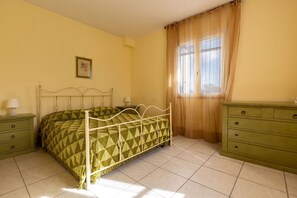 A room with a bed, a dresser, a nightstand, a picture on the wall, and a window with curtains. - Villa Micelli by BarbarHouse (Campomarino)