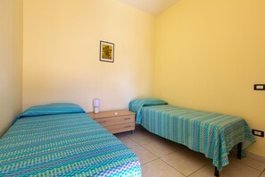 A small, single-room accommodation with two beds, a bedside table, a lamp, and a framed picture on the wall. - Villa Micelli by BarbarHouse (Campomarino)