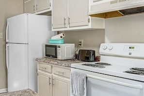 Eine Küche mit weißen Geräten, darunter ein Kühlschrank, eine Mikrowelle, ein Toaster und ein Herd.