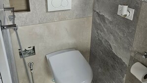 Une salle de bain moderne équipée de toilettes, d’une douche et d’une fenêtre.