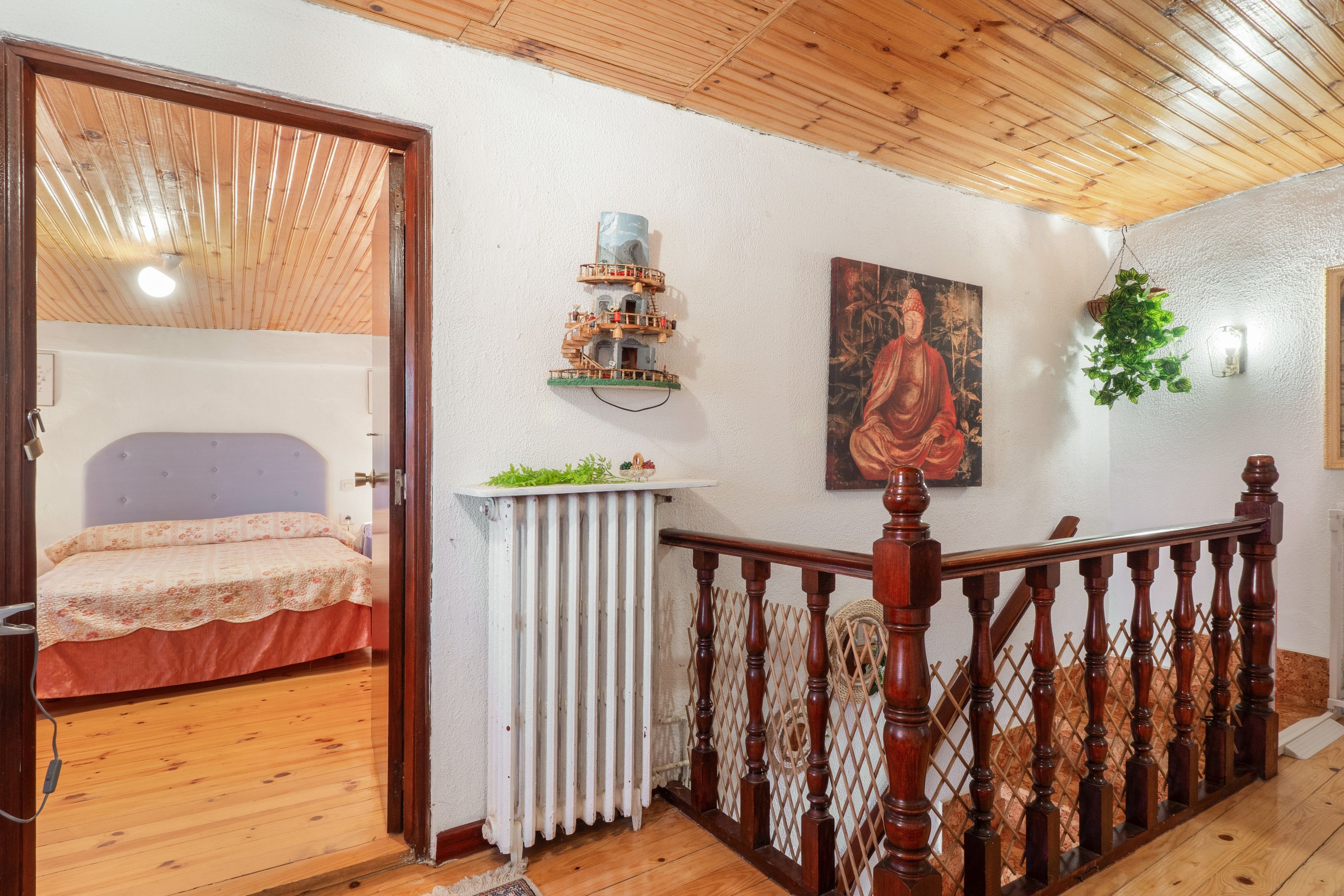 A room with a bed, a radiator, a wooden staircase, and a painting on the wall.
