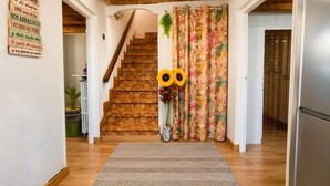 Un escalier en bois menant à un palier agrémenté d’un rideau à motifs floraux et d’une décoration en forme de tournesol.