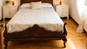 Un plafond lambrissé en bois, un lit avec une tête de lit en bois, deux tables de chevet avec des lampes, un miroir fixé au mur et une fenêtre avec des rideaux.